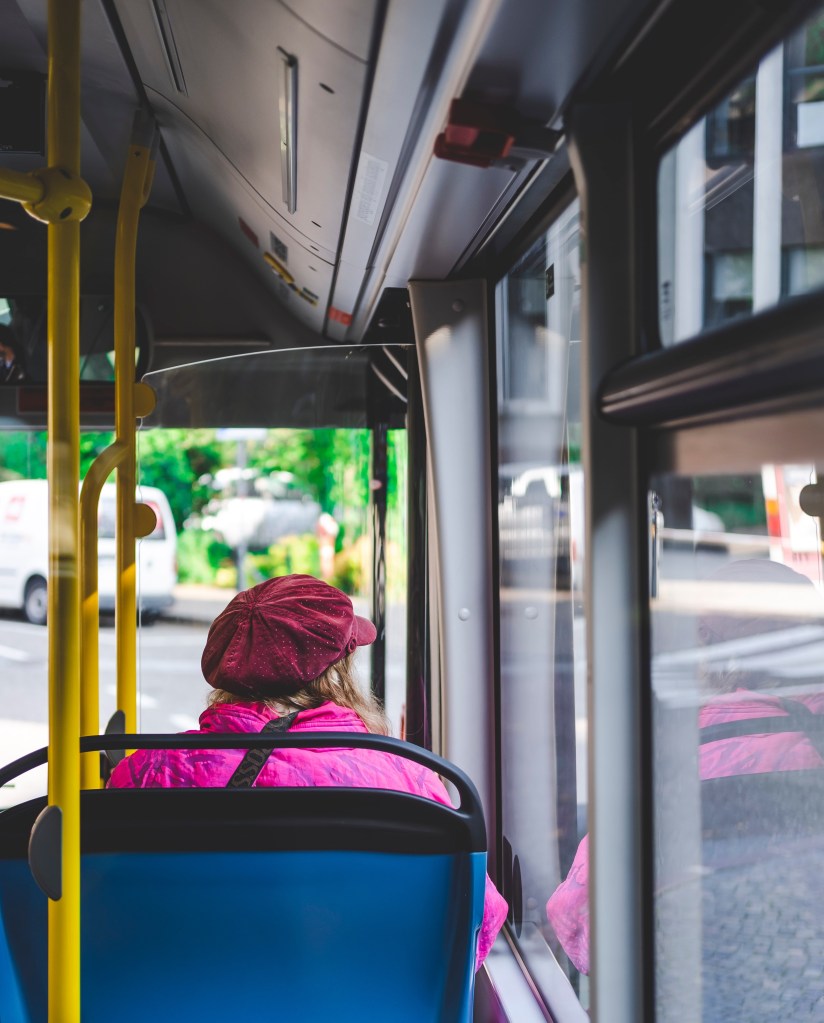 Woman wearing pink sitting on a bus - view from behind.